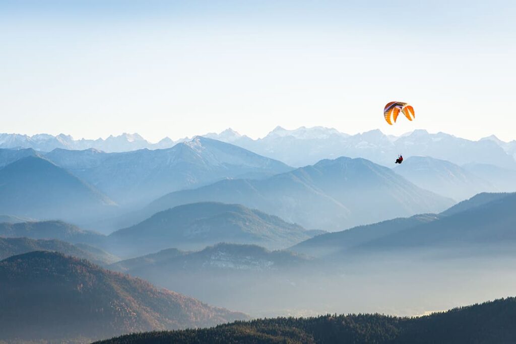 sprawling mountain view with soaring person parasailing in distance